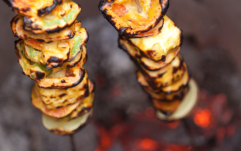 skewered vegetables being lowered into tandoor oven